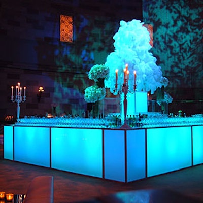 The focal point of the space was a large central bar crowned with a trio of massive arrangements with white feathers.
