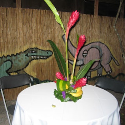 The 'Beastkeeper' private cocktail party featured seating with tropical floral and fruit centerpieces and a thatched backdrop brightly painted with animals.