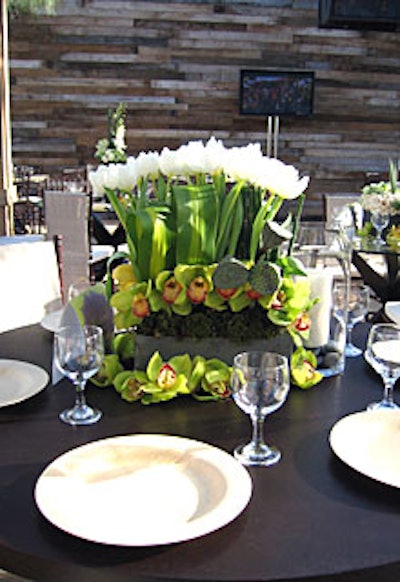 Centerpieces for the viewing party included an arrangement of white roses, orchids, or tulips set in ornamental cabbage, moss, and horsetail.