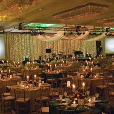 The stage combined shimmer drape with an LED light curtain, two metallic gold-columned screen surrounds, and a 30-foot-wide gold contra-H canopy.