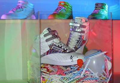 A plastic box filled with celebratory candles and balloons displayed a festive pair of 25th anniversary Reeboks.