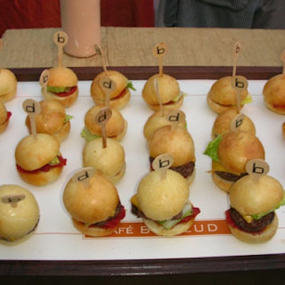Mini cheeseburgers topped with onions, lettuce, and tomato were held together by a stick and served on Café Boulud trays.