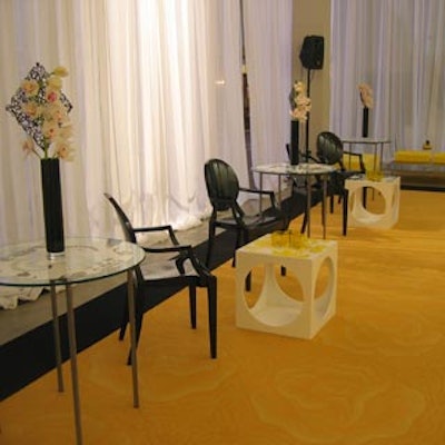 Arrangements of small glass side tables, black Ghost chairs, and ornate cube tables sat atop a massive, yellow rose-patterned carpet with a black border from Interface Flor.