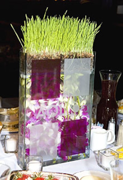 Hand-applied translucent violet and frosted silver vinyl decorated glass vases filled with orchids and topped with wheatgrass.