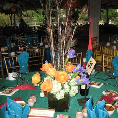 Shed peacock feathers accented an orange rose, blue iris, and antique green hydrangea centerpiece set in Spanish moss.