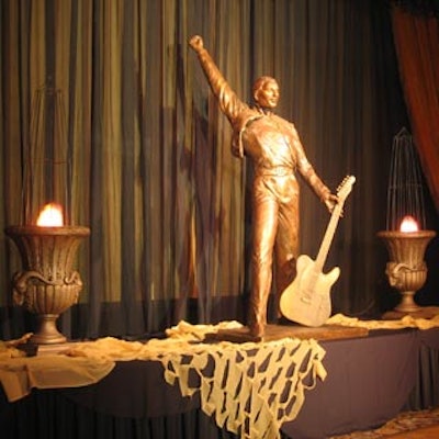 A golden statue of a guitar player accepting the adulation of his fans occupied a riser at the back of the ballroom.