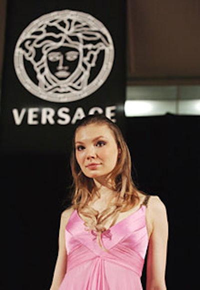 Alit-up Versace logo served as the backdrop for models walking in ’60s-inspireddaywear and jeweled evening gowns.