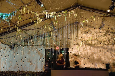 A wall of more than 700 custom-made lightbulbs hung from the ceiling of the garden tent, which also featured flowering branches and bushes.