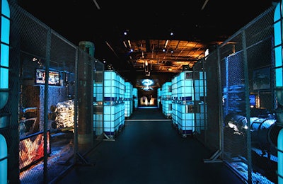 A hallway flanked by chain link and illuminated blue cubes guided guests into the main space.