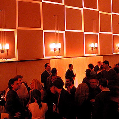 Guests mingled in the main dining room of new restaurant Town, which includes a wall backlit with staggered square panels made of Anigre wood.