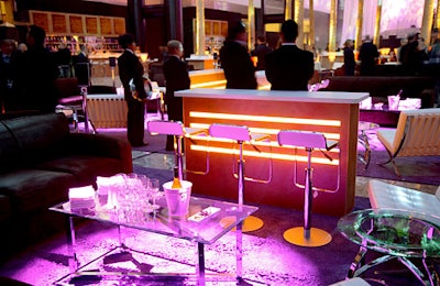 Each lounge had brown suede couches, white Barcelona chairs, glass tables, and custom-made bars lit from within. Purple area rugs and red ropes created distinct spaces. The table decor was simple, with only napkins, glasses, a chilled bottle of white wine, and a dish of olives, almonds, and cured pickles.