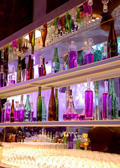 Brown, green, and crystal bottles filled with purple water—reminiscent of large perfume bottles—were reflected in the mirrors behind the bars.