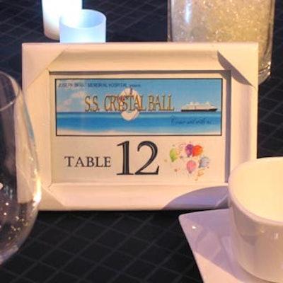 Wood frame table markers depicted a cruise ship against a blue seascape and included the name of the event, SS Crystal Ball.
