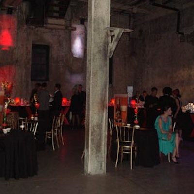 Red candleholders topped small café tables covered in black linen from Chair-man Mills.