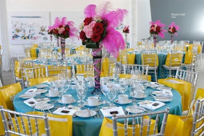Dinner table decor from design firm Make My Day included brightly coloured table scapes and burlesque theme centrepieces with pink and red roses, fishnet vase coverings, and bouffant pink feathers.