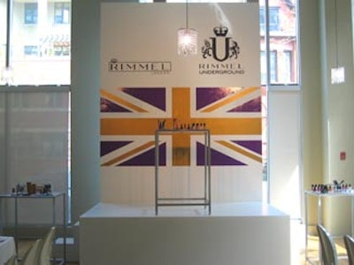 A large purple, white, and gold Union Jack poster formed the backdrop of Rimmel product display at the front of the room.