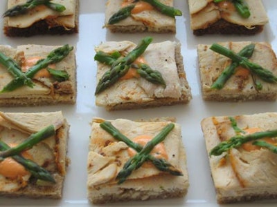 Eatertainment served lunch snacks, including square toasts topped by slices of turkey breast and crisscrossed stalks of asparagus.