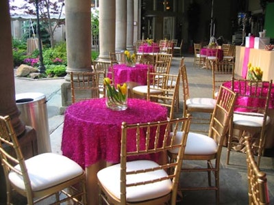 Yellow tulips in clear glass vases topped hot-pink textured linens over heavy gold underlay fabric.