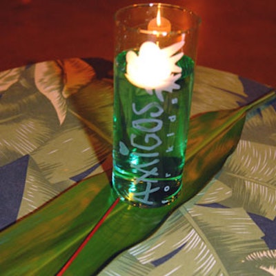 Table centerpieces mixed branded glass candles with palm leaves.