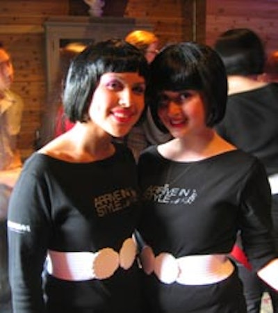 An all-female team of CHUM Television staffers dressed in black with white seashell buckle belts, black bob-cut wigs, and pink lipstick.
