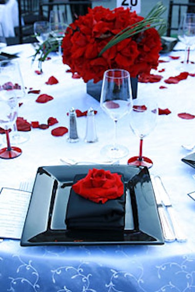 Arrangements of giant red roses made elegant table centerpieces; single blooms decked each black linen napkin.