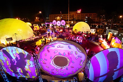 Character silhouettes and doughnut images were projected onto large circular structures surrounding the outdoor space.