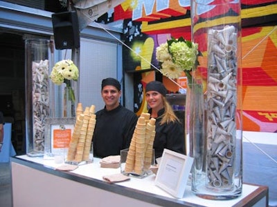 Caterwaiters from Core Event Staffing stood behind an ice cream station provided by By David’s Catering with two tall cylinders filled with decorative silver ice cream cones on both sides of the bar.