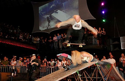 A female volunteer from the crowd did splits over two ramps while a skater jumped over her.