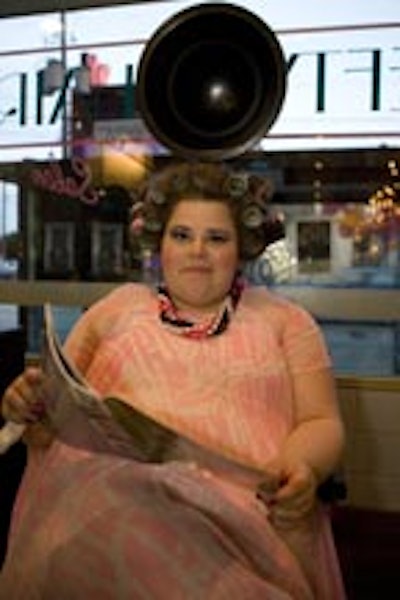 An actress in costume stood behind a prop hair dryer in a faux salon vignette from the movie.