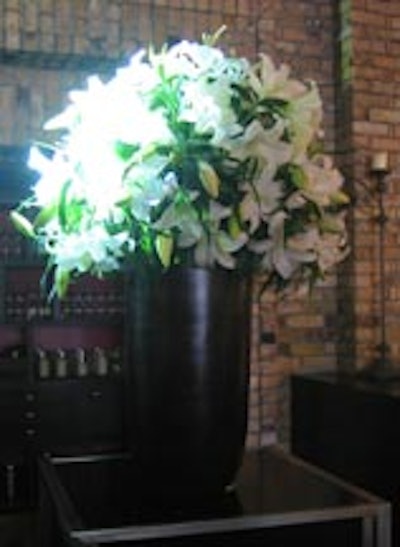 A massive arrangement of lilies from Forget Me Not Flowers in a tall black vase stood atop a black cocktail table from Contemporary Furniture Rentals.