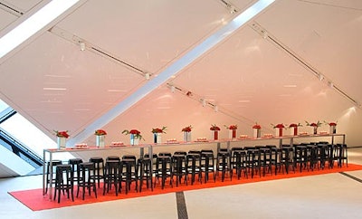 A striking red carpet runner from Contemporary Furniture Rentals formed the base of a sitting area with a long, red high-top table flanked by black Louis Ghost stools.