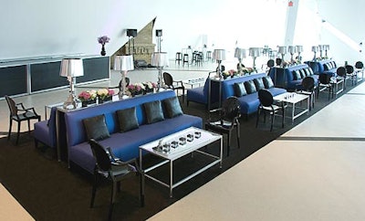 Another lounge space featured periwinkle sofas with white coffee tables on a black carpet runner.