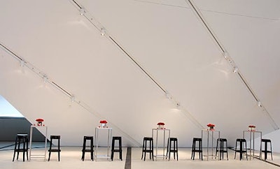 Mirrored containers filled with red roses topped white square cocktail tables paired with black Louis Ghost stools.