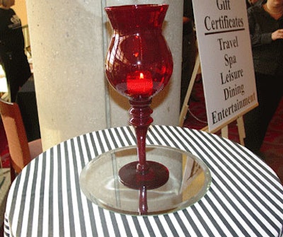 Red glass decanters set atop mirror rounds added an elegant touch of color to the black-and-white striped high-top tables.