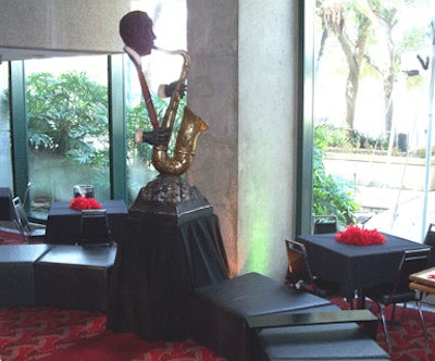 A colorful statue of a saxophonist set atop a rotating pedestal kept watch over Grand Event's black leather modular ottoman seating area situated beneath the main staircase.
