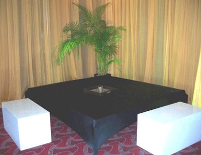 Conversation nooks were created with platform loungers covered in black spandex set around plexiglass cube tables with gold matte sheer draping accenting the walls.