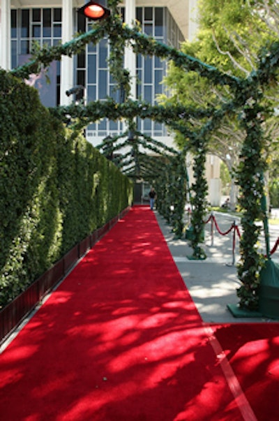 Foliage hung over the red carpet and on a wall behind it.