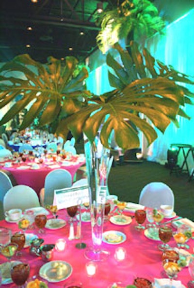 Round tables took on a new contemporary shape with stretch coverings in green, orange, fuchsia, and yellow, topped with cylinders filled with tropical branches.