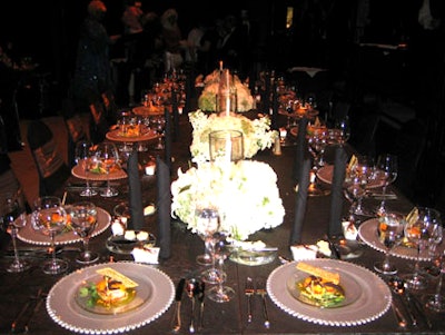 The stage featured one long table for the title sponsor with 16 place settings and four centerpieces each with a linear hurricane glass encompassed by a pave-style floral arrangement.