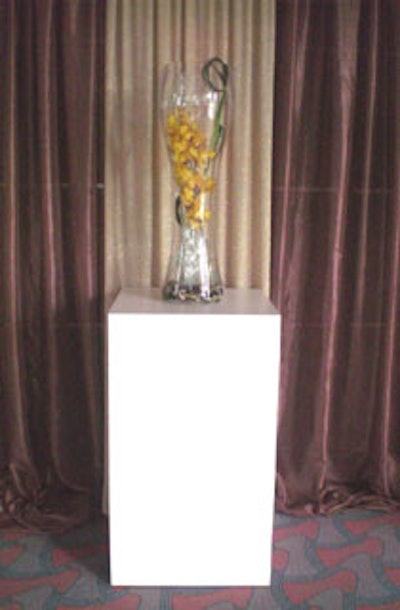 A tall glass vase filled with river rock, and chocolate cymbidium orchid stems woven with a silver wire mesh added another visual element to the lobby.