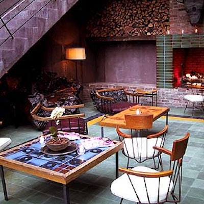 A room adjacent to the outdoor patio features cozy lounge seating in front of a big fireplace, with glass walls for a good view of the action outside.