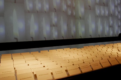 A large projection of candle flames made for a dramatic backdrop for guests' name cards and gave light to the museum's entry hall.