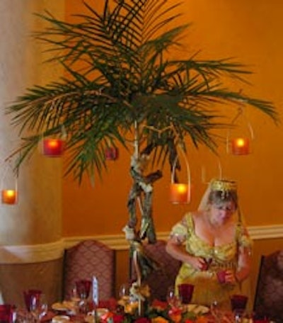 One of two centerpieces supplied by Designing Trendz consisted of a three-foot gold-coloured pole wrapped in twisting bark, topped with cascading palm leaves and hanging votives, and based in burnt orange roses and greenery.