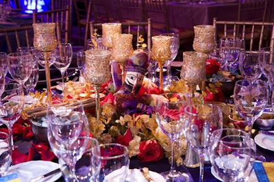 Tabletop decor included Rajasthani puppets, baskets of naan bread, red rose arrangements, gold glitter-sprayed leaves, and mosaic-tiled candleholders.