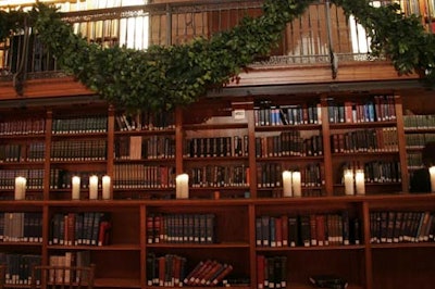 Candles and boughs of greenery adorned the bookshelves in the dinner space.