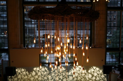 Fifty tubelike lightbulbs hung from each custom chandelier. Additional lighting elements included a leaf-patterned projection.