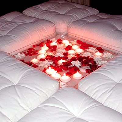 White bed seats were decorated with a shallow glass tray filled with water, white globe candles, white flowers and red rose petals.