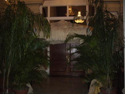 A grass hut awning and potted ferns created a shelter for the dining room entrance.
