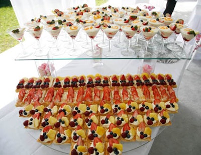 Thierry's Catering set up a two-tiered dessert table featuring passion fruit champagne parfait with fresh berries and individual fruit tartlets.
