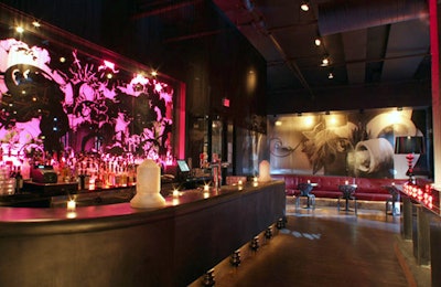 A dramatic sandblasted mirror layered in vinyl provides a backdrop for the bar, fashioned in curved steel, on the main floor.